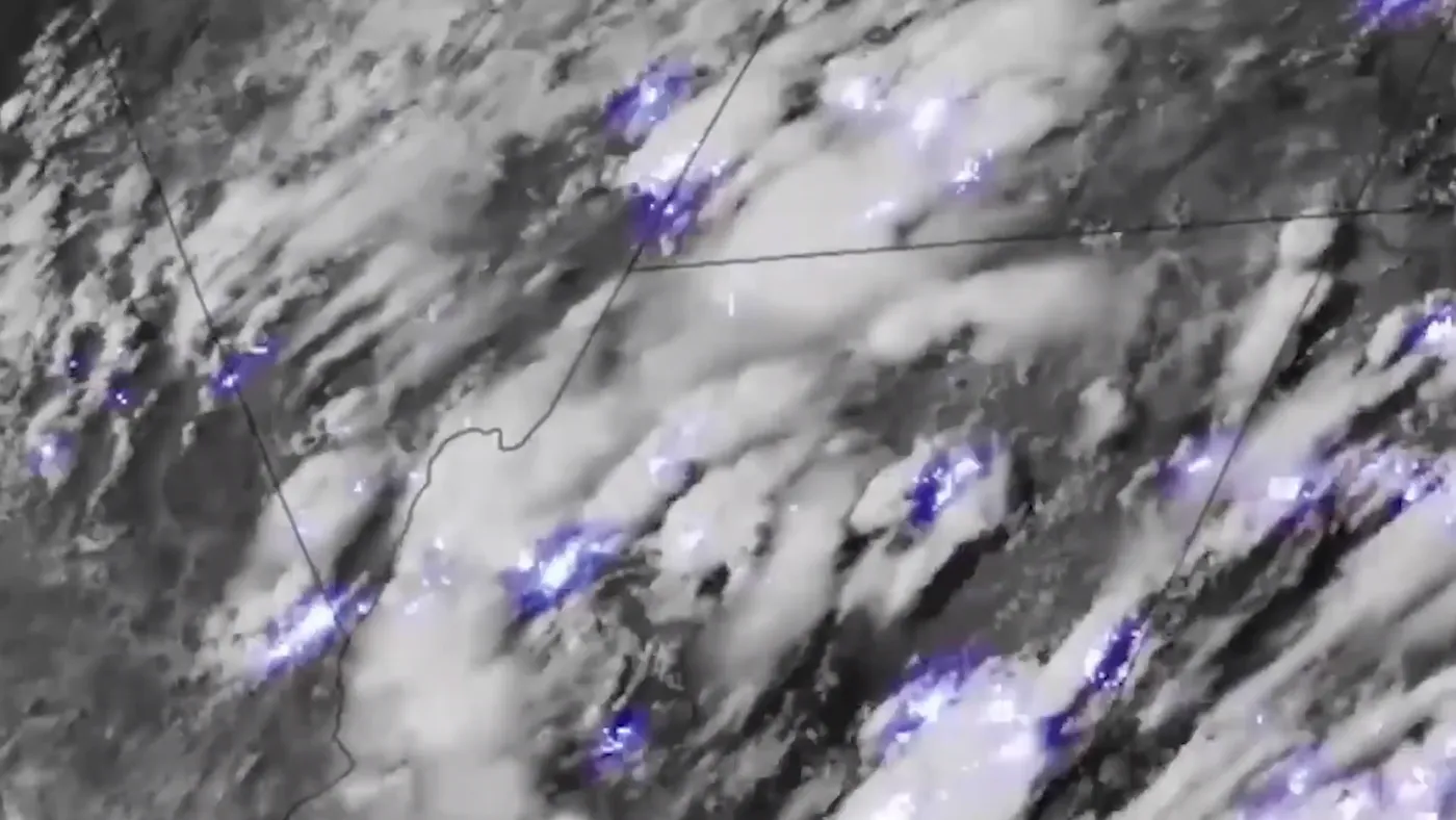 Satellite view of thunderstorm flashes lighting clouds from above at night