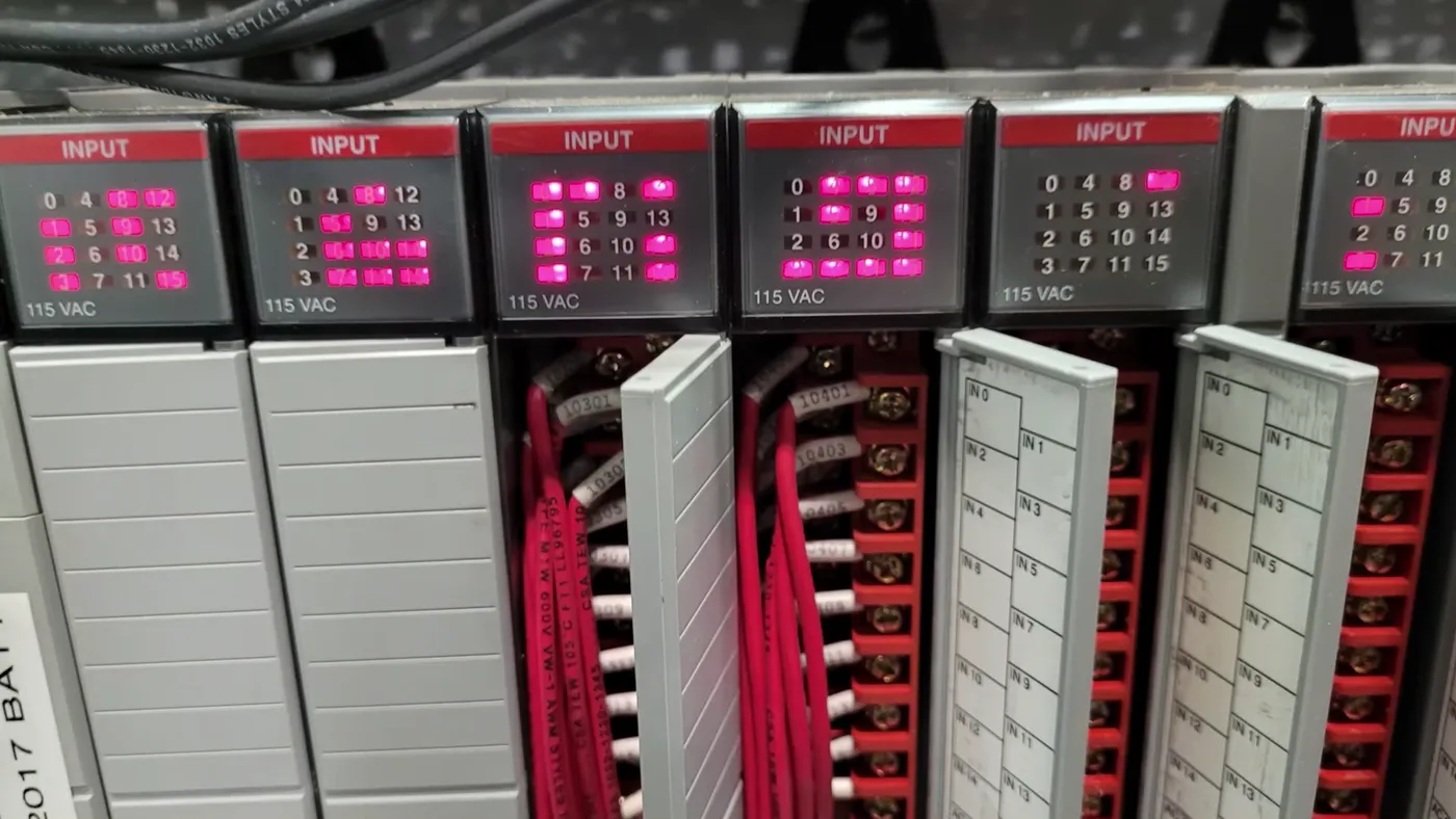 A rack of industrial controller input cards with their indicator lights on